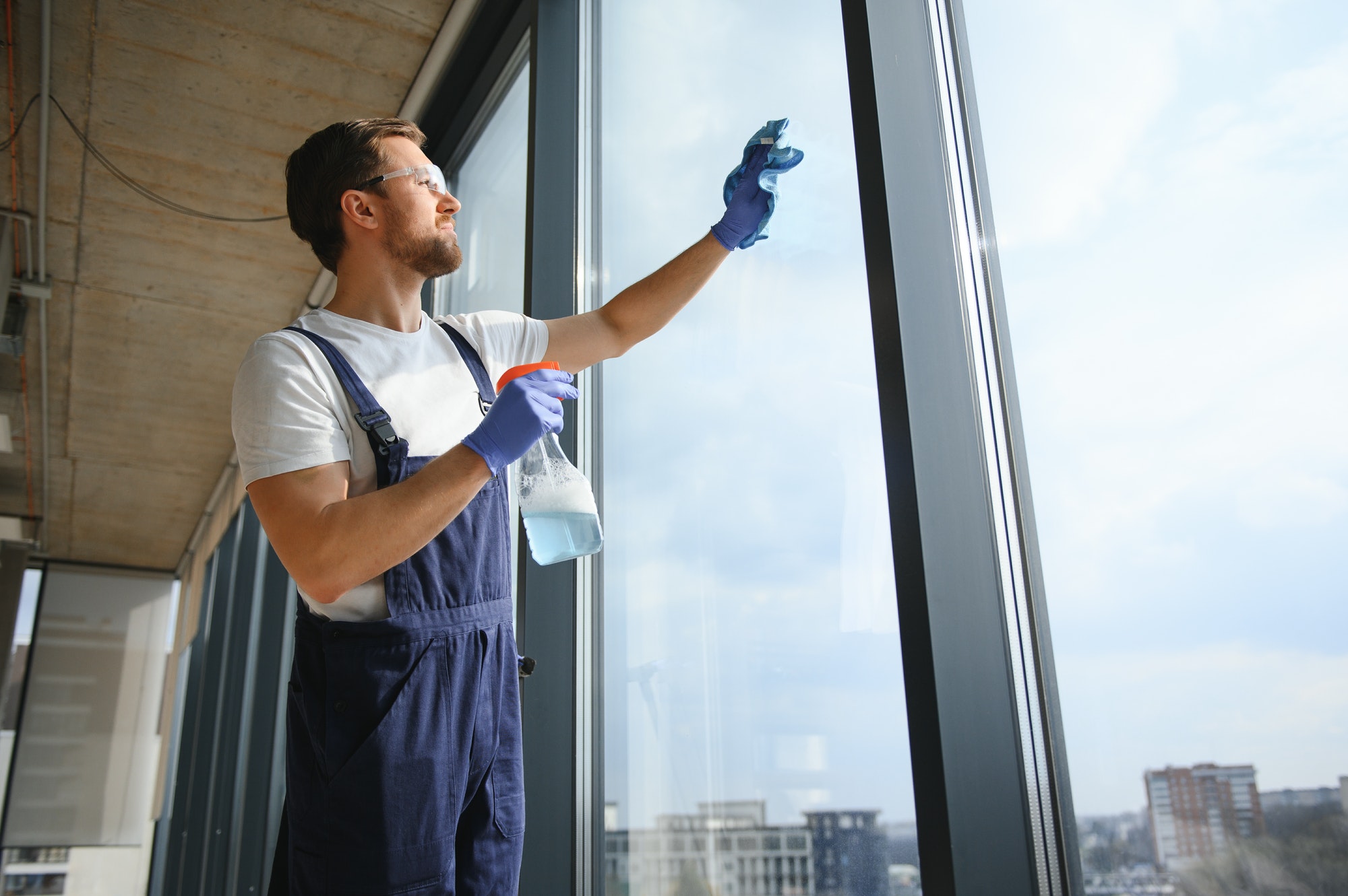 An employee of a professional cleaning service washes the glass of the windows of the building.